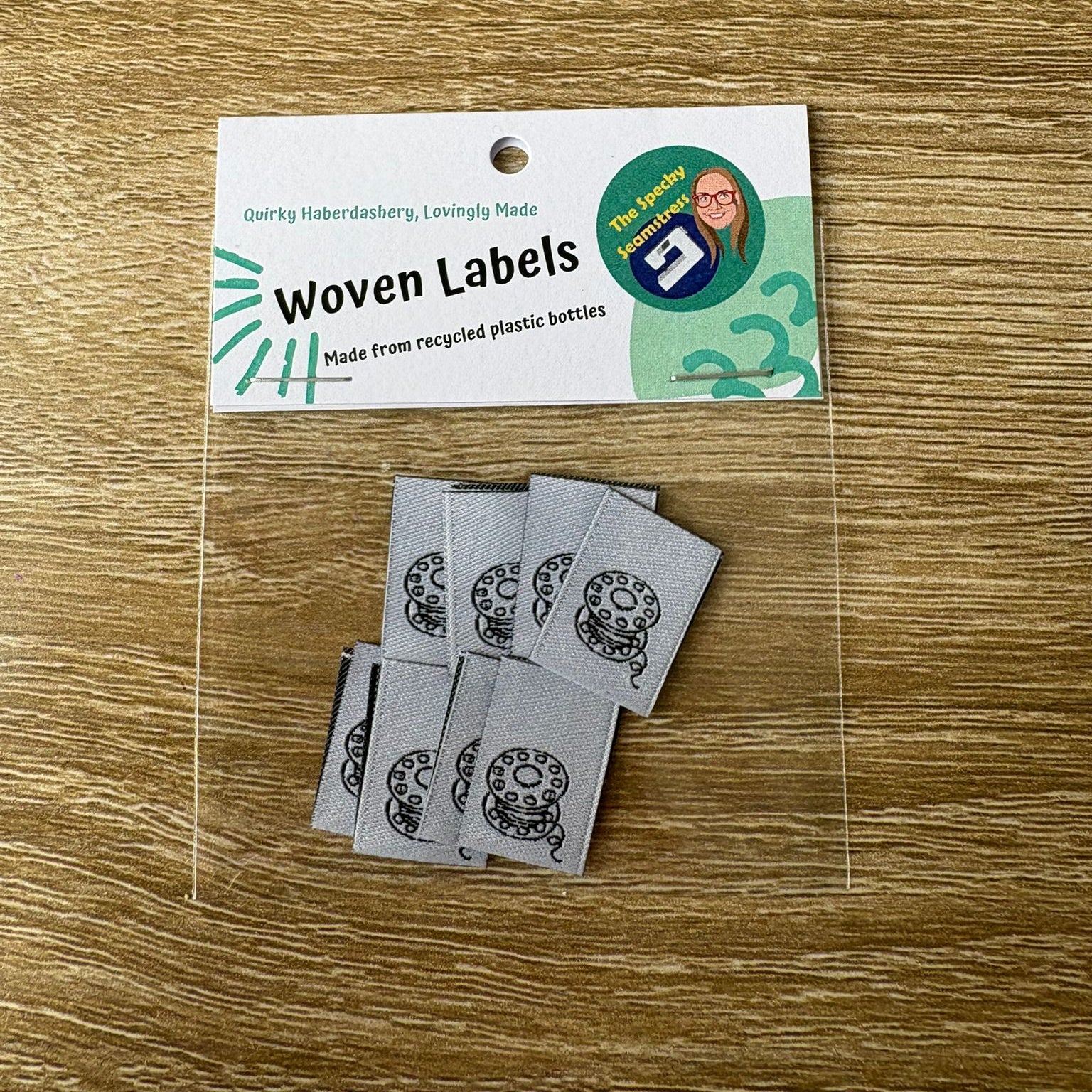 8 Mini Bobbin Woven labels with a tag on a wooden surface