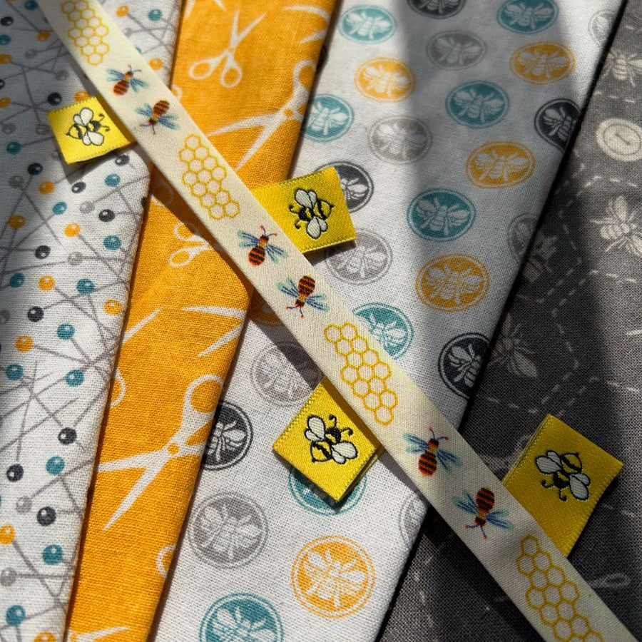 Bees  bias and labels displayed on quilting fabric.