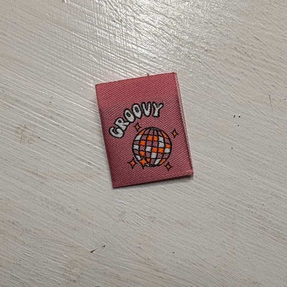 Small pink label with 'Groovy' text on a wooden surface