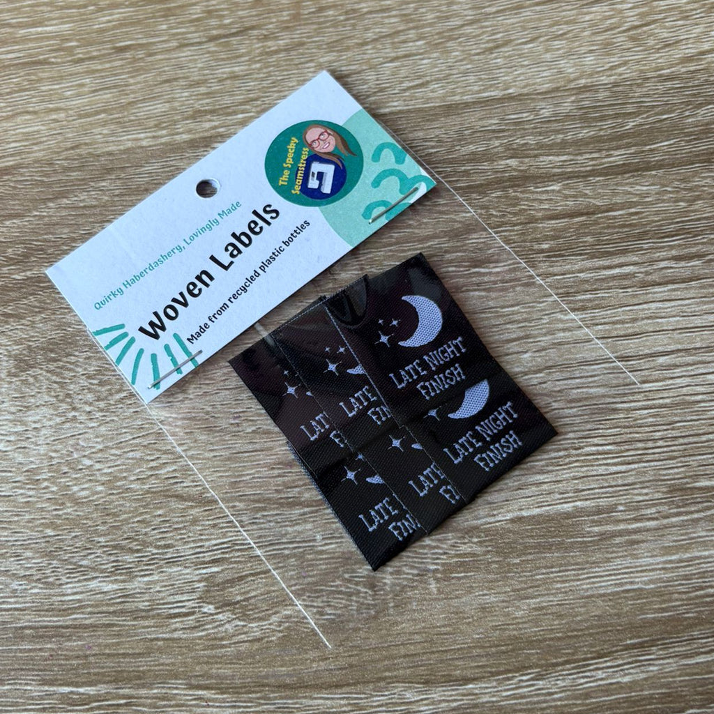 Woven labels in a clear bag with a label card on a wooden surface