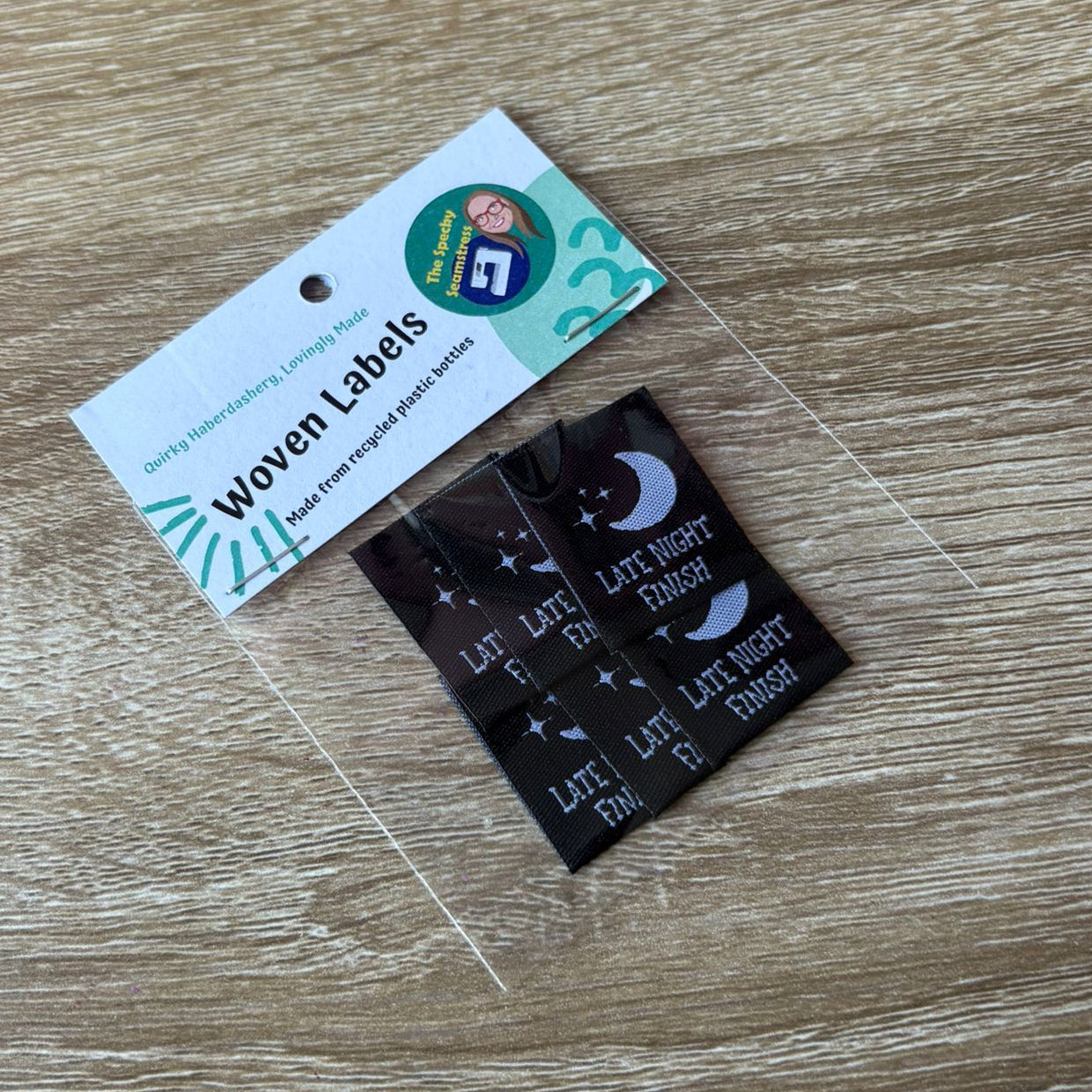 Woven labels in a clear bag with a label card on a wooden surface