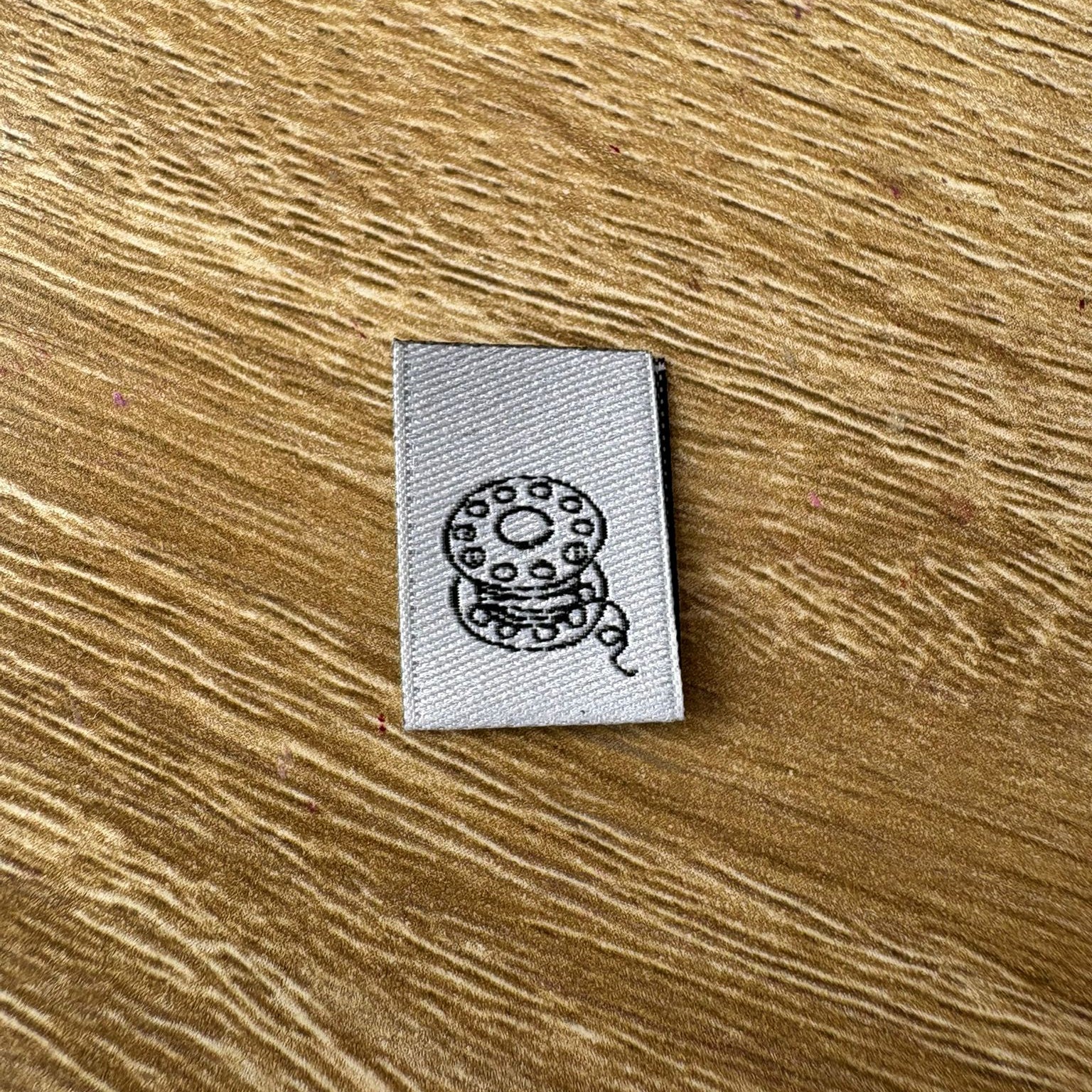 Wovenlabel with spool design on a wooden surface
