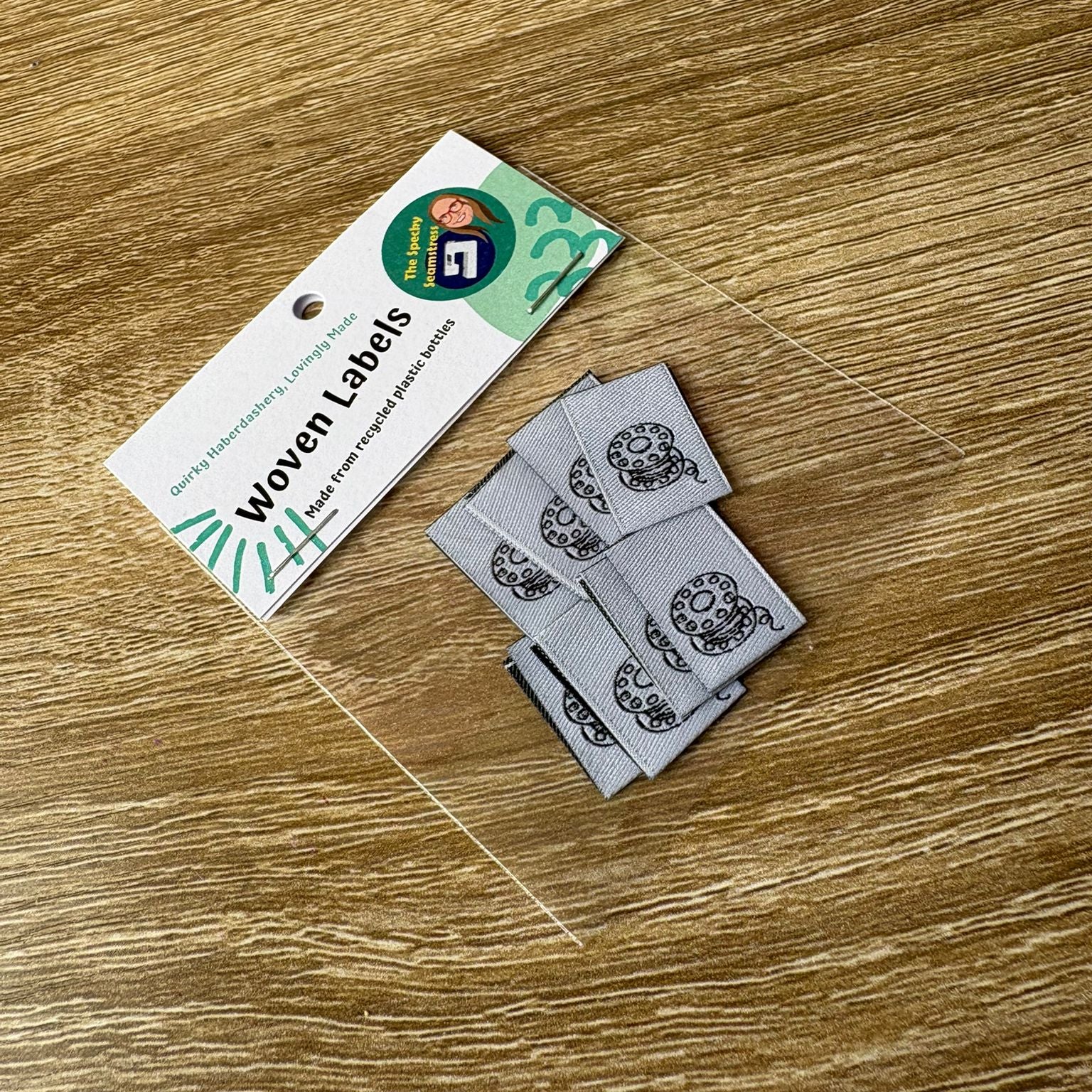 8 Mini Bobbin Woven labels with a tag on a wooden surface