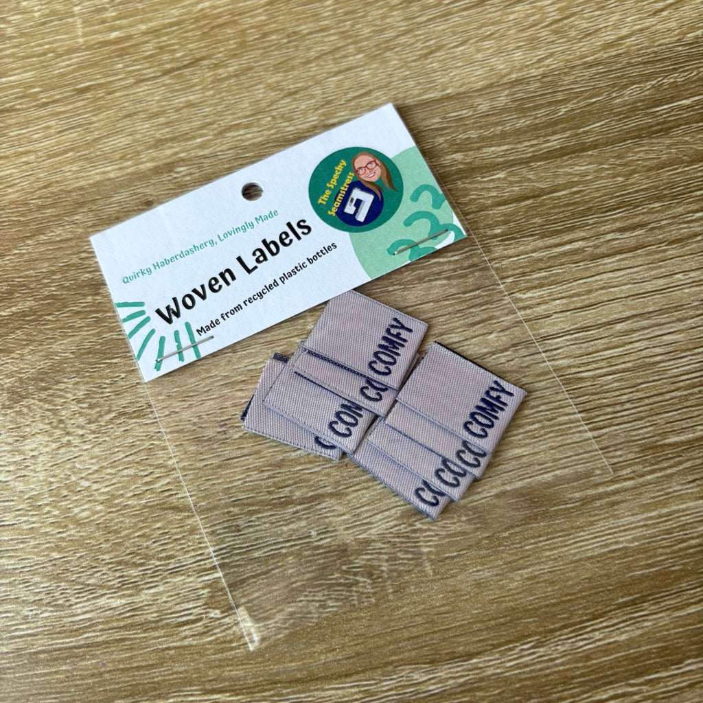 Woven labels on a wooden surface with a label card in the background.