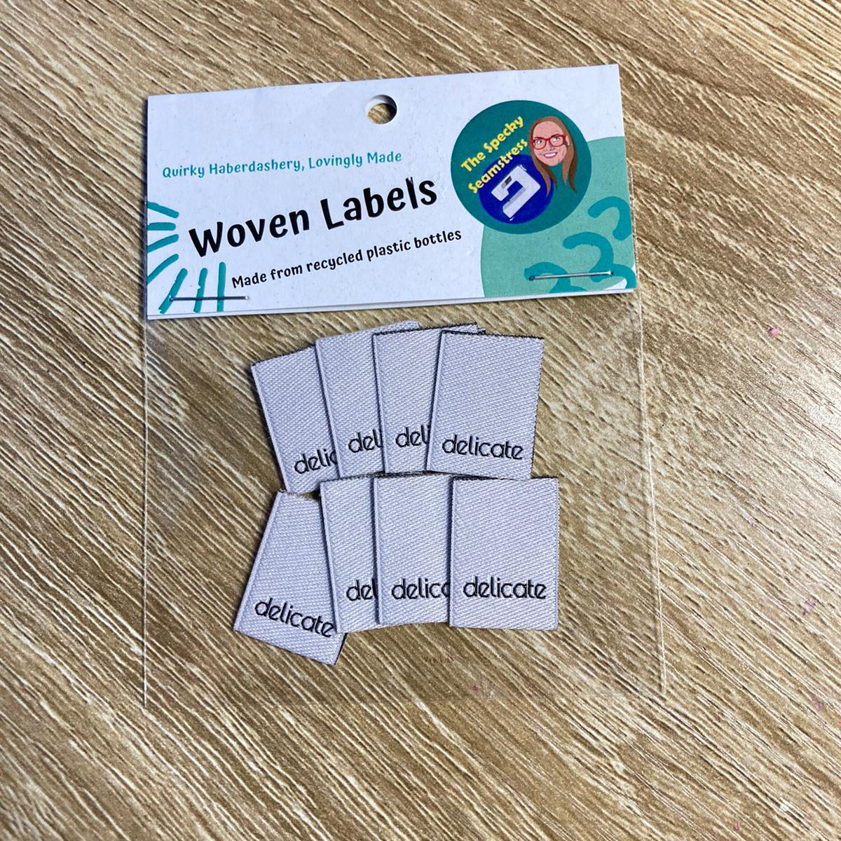 Woven labels with 'delicate' text on a wooden surface
