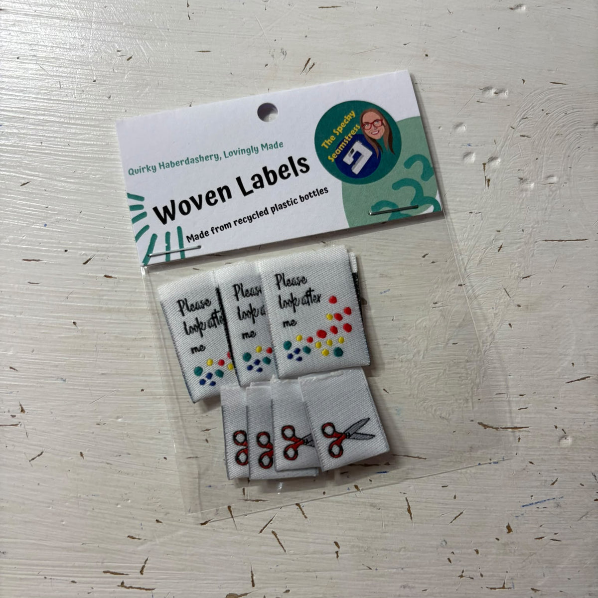 A two designs of woven fabric labels, 'Please Look After Me' and Mini Scissors on a white background.
