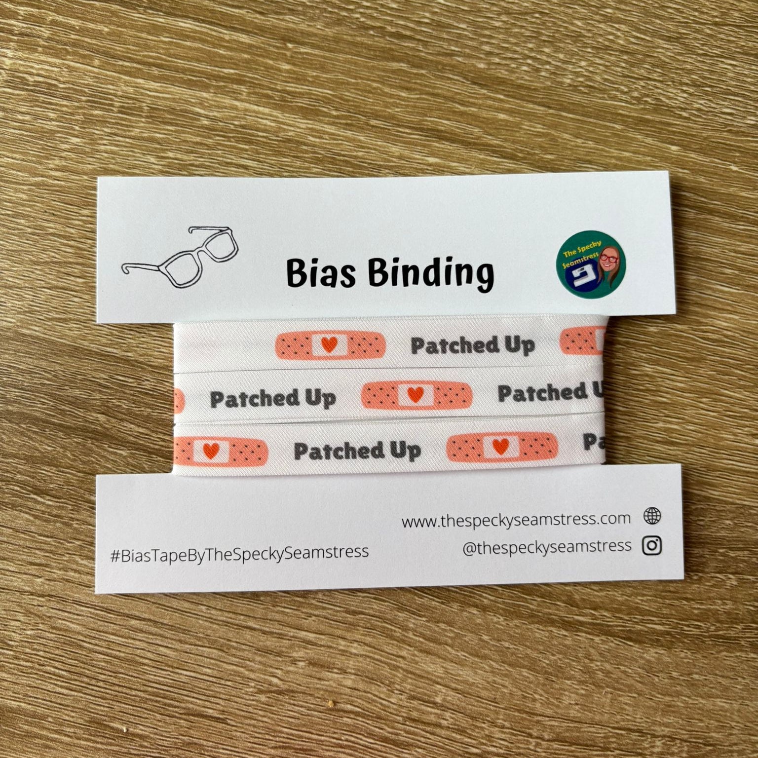 White bias with a plaster motif on a white backing card, laid on a wooden background. 