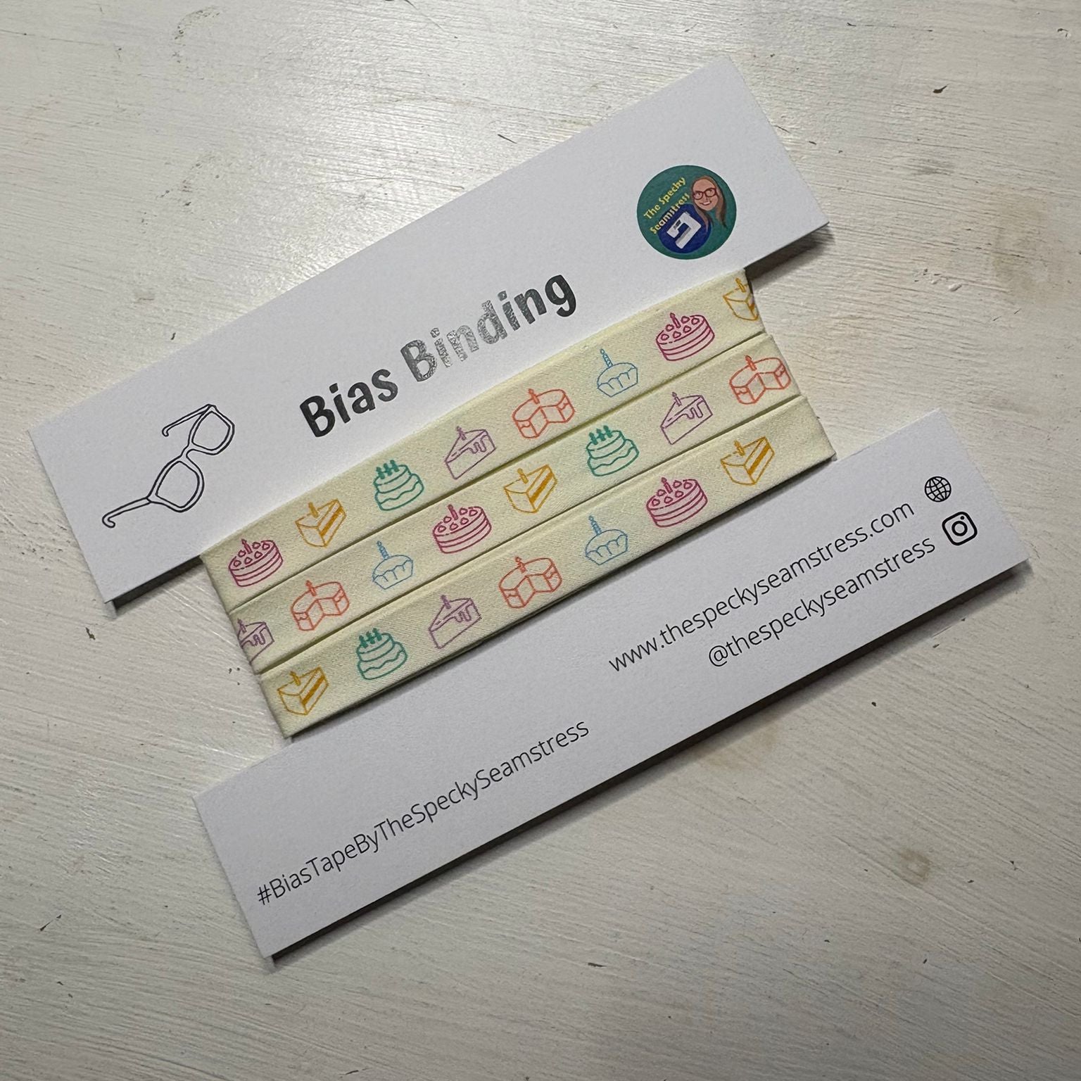 Piece of Cake Bias binding on a white card, on a white wooden table. 