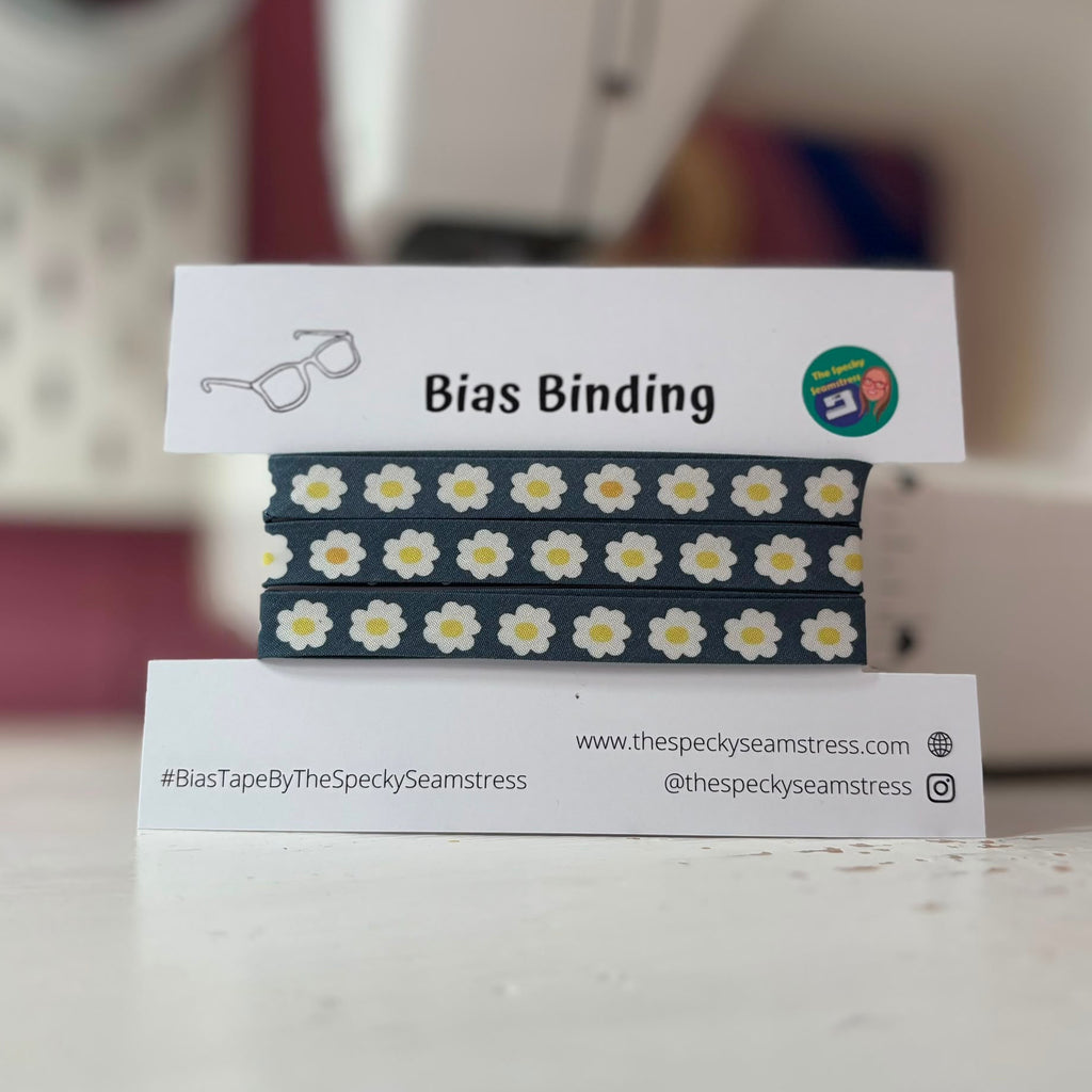 Bias binding with daisy pattern on a stand with branding information.