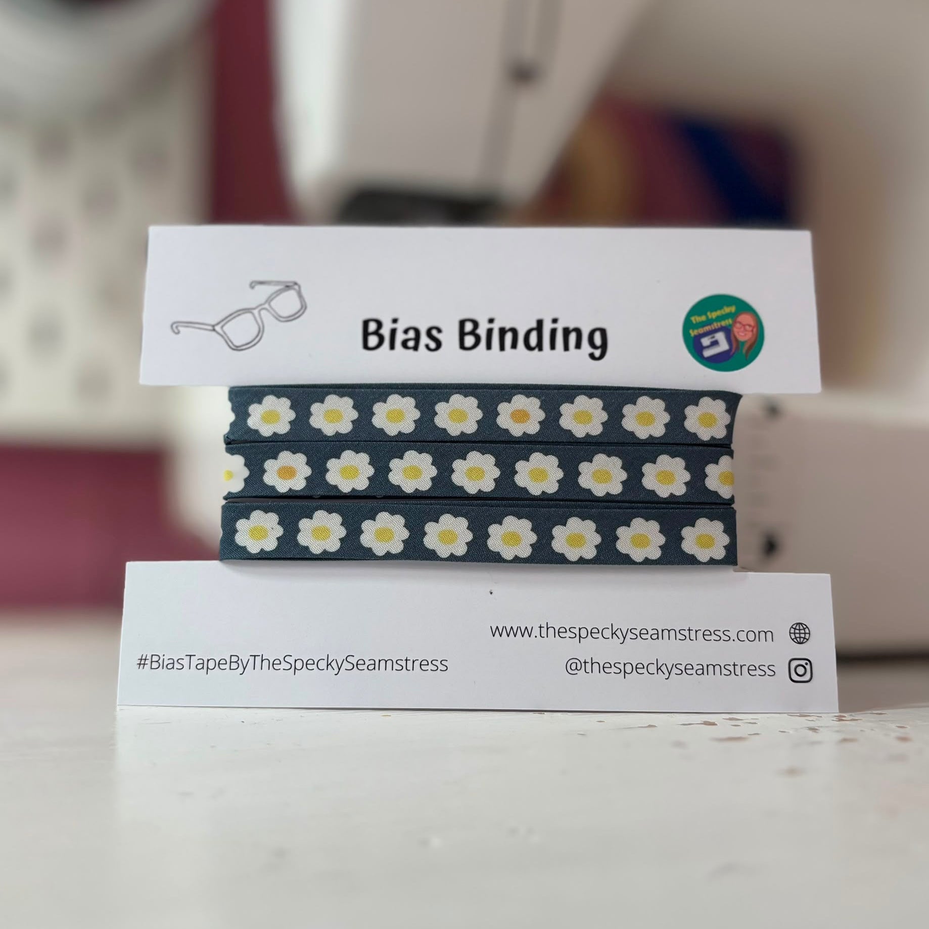Bias binding with daisy pattern on a stand with branding information.