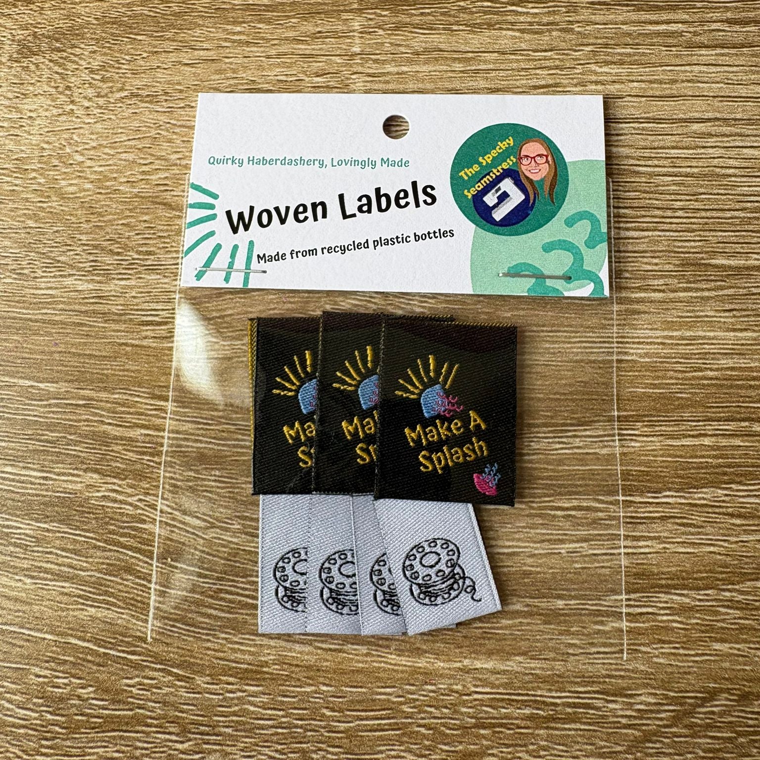 Woven labels with 'Make A Splash' and a Mini Bobbin text on a wooden surface