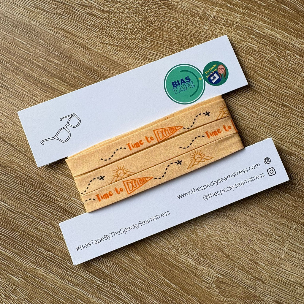 Peach patterned bias on a white backing card, placed on a wooden surface. 