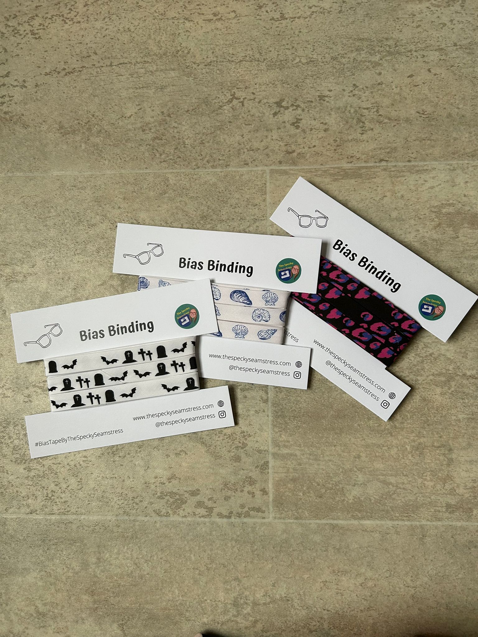 Three Northern Sewl Sisters bias designs wrapped around a white cardboard display cards on a cream background.