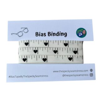 Whit tape measure style bias tape with black details on a white cardboard backing card.